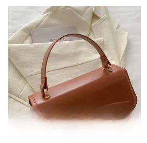 Close-up of brown matte leather handbag with metal fastener on white blazer