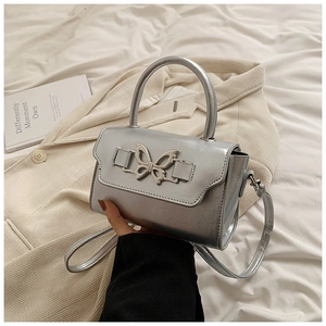 Detailed view of silver bow-knot buckle on a shiny metallic crossbody handbag
