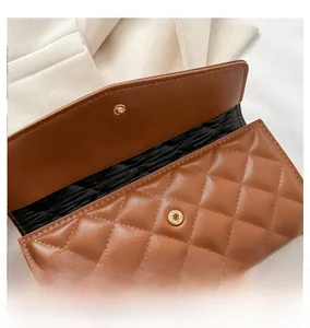 Detail of dark brown quilted long wallet with golden magnetic buckle and fine stitching