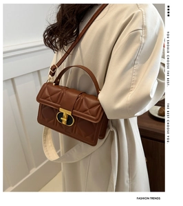 Close-up of brown quilted leather bag with gold T-shaped clasp and handle detail