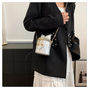 Detail of silver metallic bucket bag with quilted design and gold chain shoulder strap