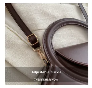 Macro view of adjustable golden buckle and fine stitching on a brown leather bag strap