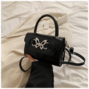Detail of black faux leather handbag with silver butterfly buckle and stylish handle