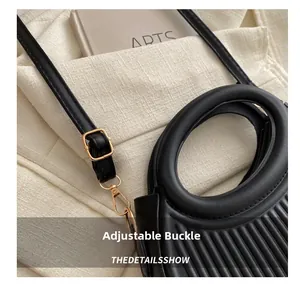 Detail of black crescent bag showing vertical pleats and golden adjustable strap buckle