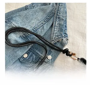 Detail of plush cow print shoulder bag with black leather handle and gold metal rings