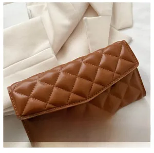 Detail of deep brown quilted stitching and soft texture on a fashion clutch bag