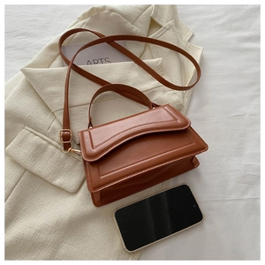 Caramel brown leather mini square bag on blazer showing compact size and texture