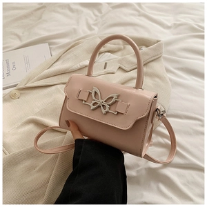 Detail of pink PU leather handbag with metallic butterfly clasp on beige blazer
