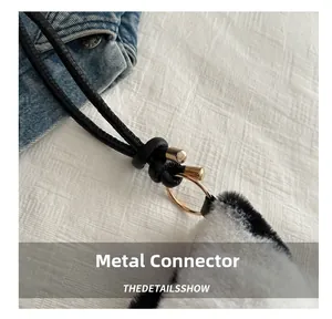 Close-up of golden metal ring buckle connecting black and white plush shoulder bag