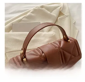 Detail of caramel brown quilted leather handbag with gold twist lock and sturdy handle