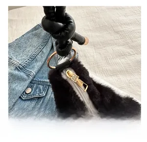 Detail of plush black and white shoulder bag featuring a smooth gold zipper and knotted handle
