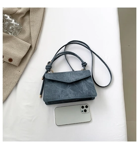 Dettaglio di una mini borsa blu scuro in denim con smartphone per confronto taglie