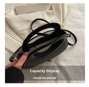 Macro view of pleated black handbag interior capacity with golden ring hardware details