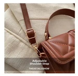 Detail view of brown quilted crossbody bag featuring golden hardware and adjustable strap