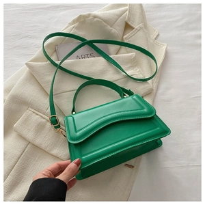 Detail of green faux leather handbag with gold metal hardware and top handle design