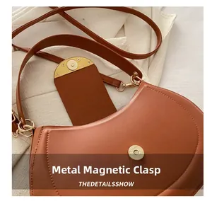 Close-up of magnetic buckle closure and stitching detail on brown vintage saddle bag