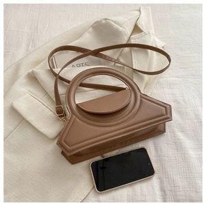 Detail of dark brown geometric crossbody bag with round handle and adjustable strap