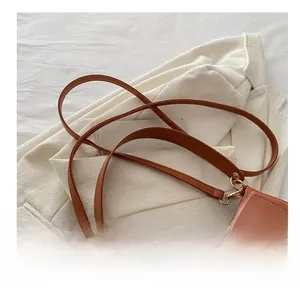 Detail of the brown leather shoulder strap and golden buckle on a vintage saddle bag