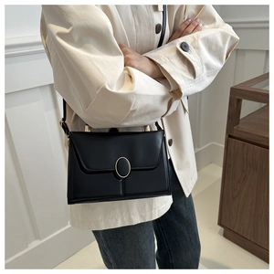 Détail d'un sac à main chic en cuir PU noir avec un fermoir ovale doré élégant