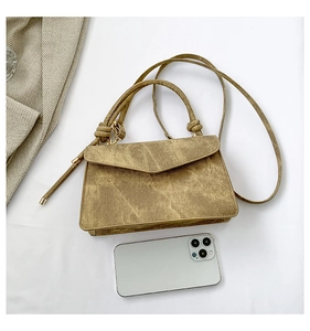 Vista dall'alto di una borsa a trapezio kaki vintage con manici a nodo e telefono per scala