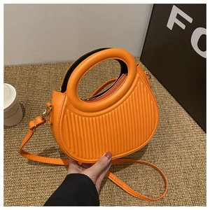 Detail of orange semi-circular crossbody bag with vertical stripe embossing and round handle