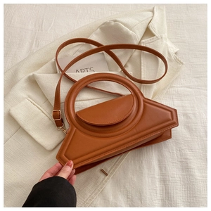 Detail of a brown geometric crossbody bag with a circular handle and matte finish