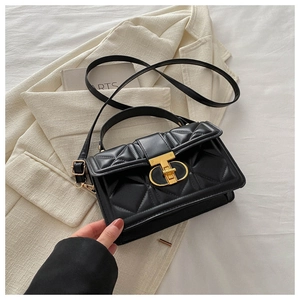 Detail of black quilted leather handbag with gold geometric clasp and top handle