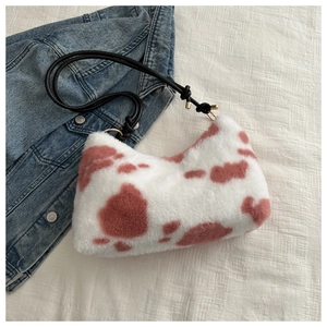 Detail of plush cow print handbag with soft faux fur and black rope shoulder strap