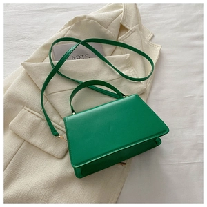 Detail view of emerald green trapezoid mini handbag with sleek leather and gold hardware