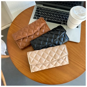 Detailed macro view of quilted envelope wallets in brown, black, and beige colors
