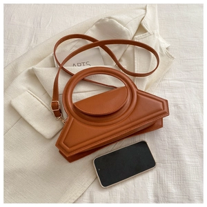 Detailed view of caramel geometric handbag with round handle and adjustable strap
