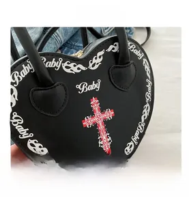 Close-up of heart-shaped punk handbag with gothic cross and flame print design