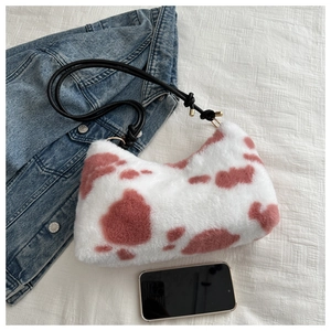 Close-up of plush shoulder bag with pink cow print and black rope knot strap detail
