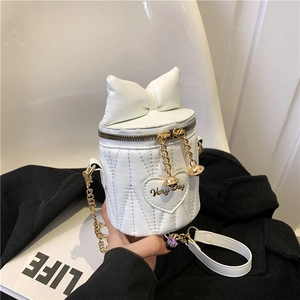 Quilted white bucket bag with large leather bow and gold chain strap in hand