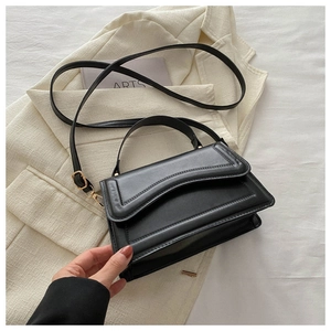 Detail of black matte leather bag with wave-edge flap and elegant gold hardware