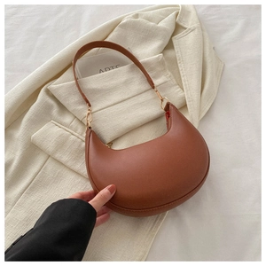 Detail of a brown PU leather hobo bag with gold zipper on a beige blazer backdrop