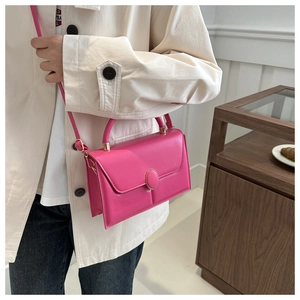 Détail du sac à bandoulière rose en cuir PU avec boucle métallique dorée sur le rabat