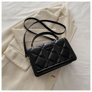 Detail of black quilted PU leather bag with gold hardware on minimalist outfit