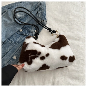 Detail view of cow print plush shoulder bag with brown patterns and knot strap