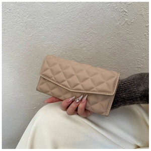 Detail of beige quilted envelope clutch bag with elegant rhombic texture and flap