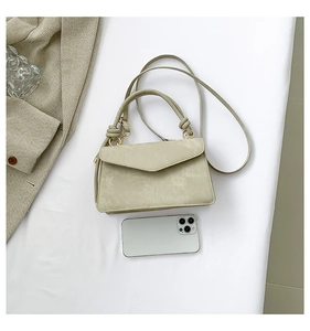Dettaglio della piccola borsa beige con telefono per mostrare la dimensione compatta