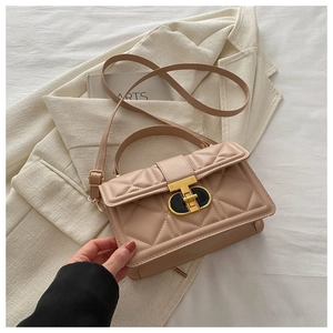 Detail of beige quilted faux leather bag with elegant T-shaped metal lock and adjustable strap