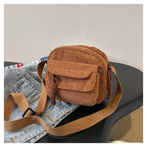 Detail of caramel brown corduroy shoulder bag with front zipper pocket and woven strap
