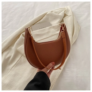 Detailed view of the brown crescent bag featuring premium faux leather and gold hardware
