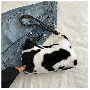 Detail of cow print plush handbag featuring soft faux fur and elegant gold hardware