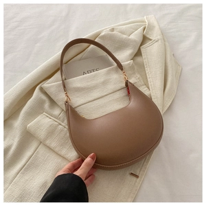 Detail of a brown PU leather half-moon shoulder bag with sleek stitching and gold hardware