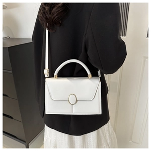 Sac à main chic en cuir PU blanc avec fermoir doré porté par un mannequin en intérieur