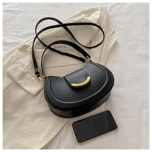 Detail of black leather half-moon bag with gold crescent buckle on white fabric