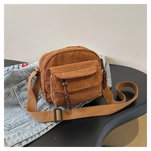Detail view of brown corduroy crossbody bag with adjustable strap and front pocket