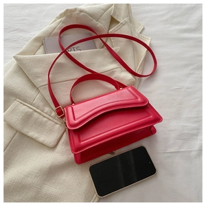 Detail of red leather crossbody bag featuring decorative stitching and adjustable strap
